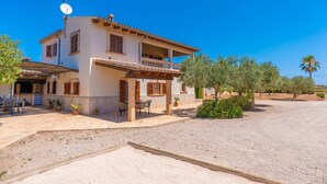 A two-story house with a balcony, outdoor seating, and a gravel driveway.