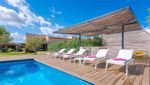 A swimming pool with lounge chairs and a pergola.