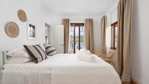 A hotel room with a large bed, a chair, a view of the city, and a balcony. - Ca Ne Margalide - Villa With Private Pool (, Illes Balears)