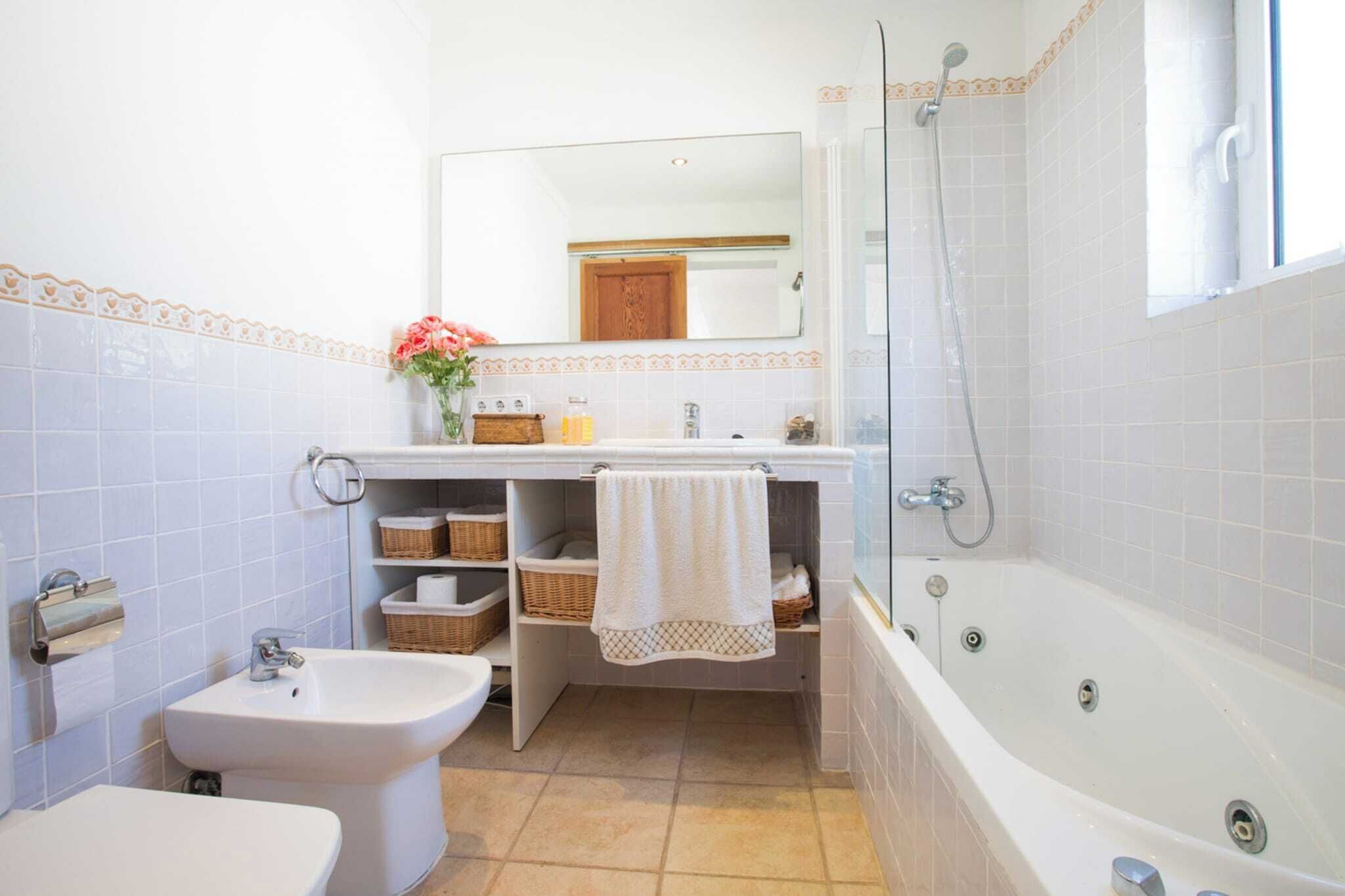 Een badkamer met een bad, een wastafel, een toilet met douchefunctie en een spiegel.