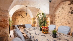 A rustic dining area with stone walls, a table set with chairs, and a fruit basket. - San Sole - Villa With Private Pool In Felanitx (, Illes Balears)