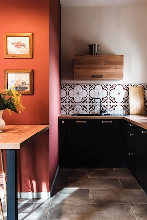 Una cocina con encimera de madera, armarios negros y salpicadero con estampado floral.
