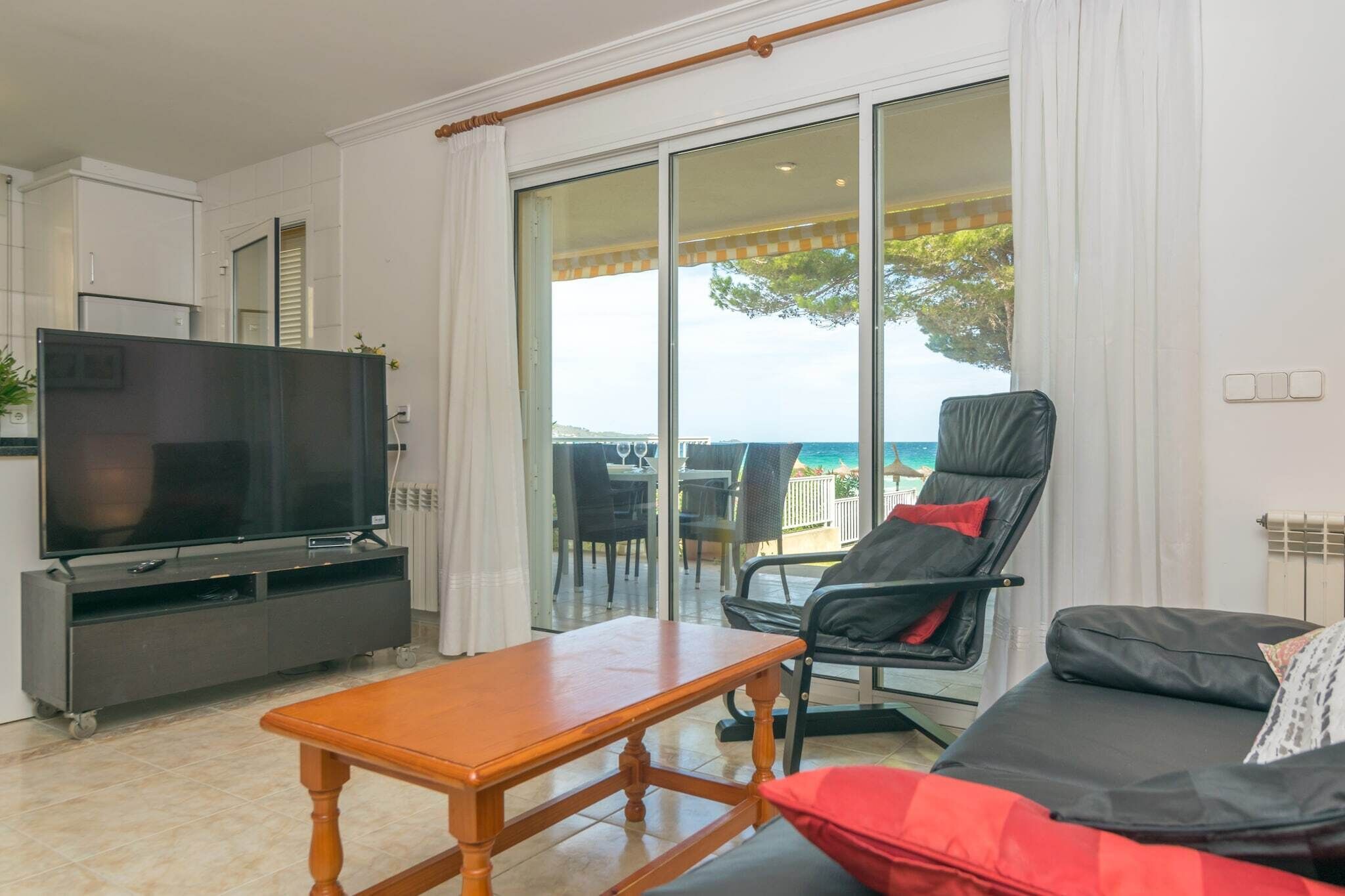 A living room with a TV, a wooden table, a sofa, and a chair.