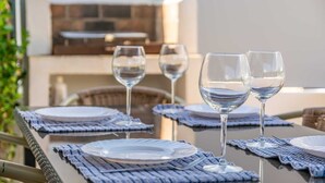 An outdoor dining area with a table set for two, featuring clear glassware and white plates on a woven placemat. - Casa Hector - Villa With Private Pool In Cala D'or (Cala D'or, Illes Balears)