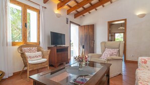 Una sala de estar acogedora con mobiliario de mimbre, una mesa de centro de madera y un televisor.