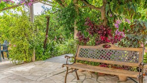 A wooden bench with a lattice backrest, surrounded by lush greenery and potted plants. - Cas Consul - Villa With Private Pool. Free Wifi (Sant Miquel De Balasant, Illes Balears)