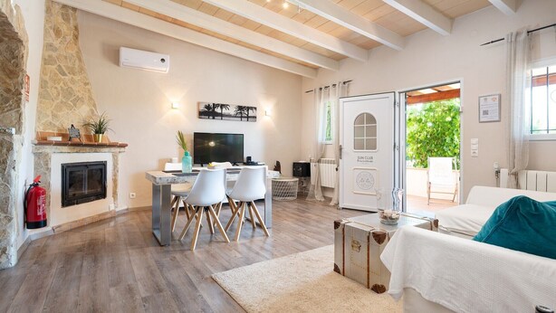 A spacious living area with a stone fireplace, a dining table with chairs, a sofa, and a view of the outdoors. - Finca Son Colom (finca Sun Club Home) - Villa (Llucmajor, Illes Balears)