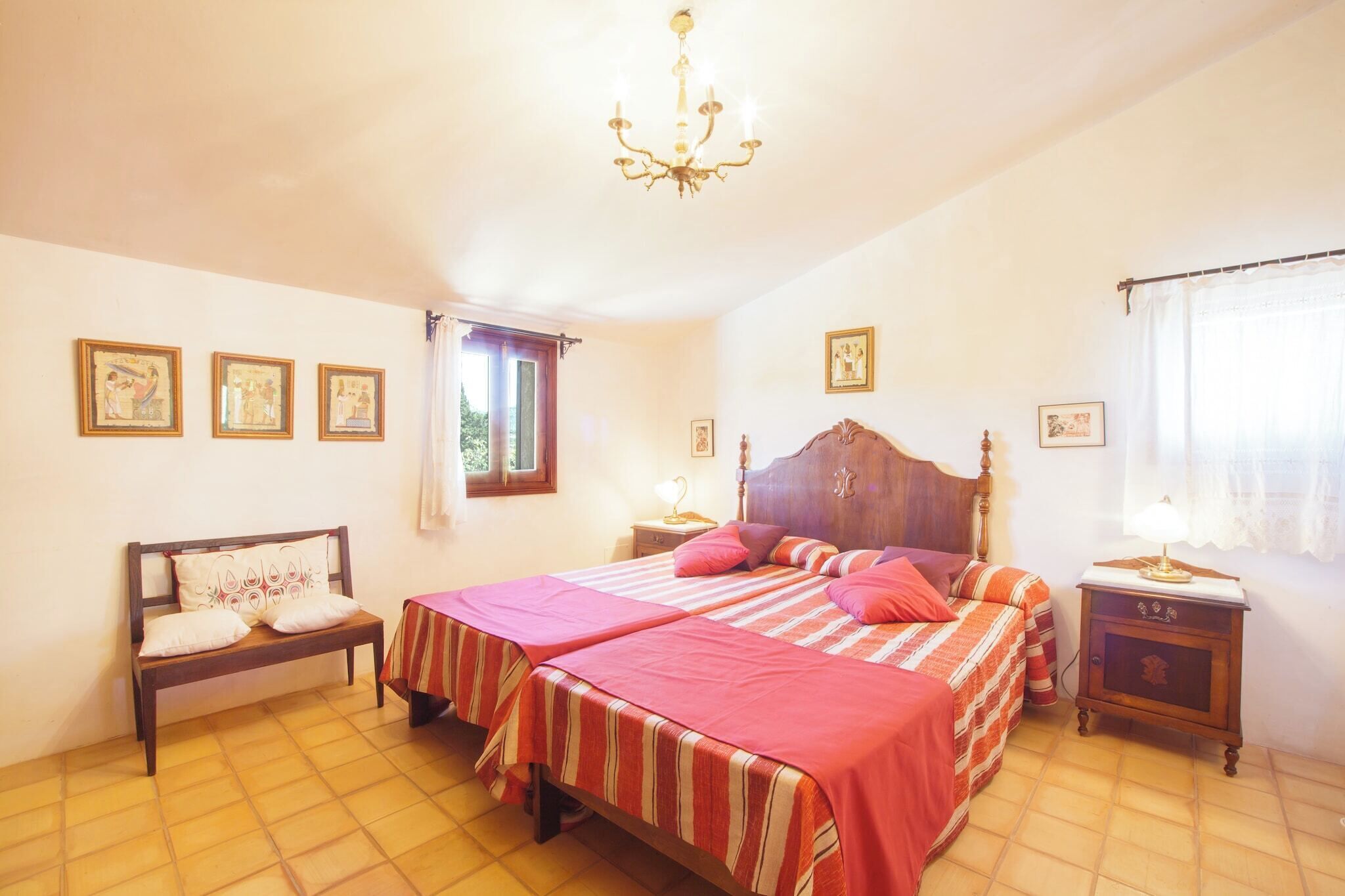 A bedroom with two beds, a wooden headboard, a nightstand, and a chandelier.