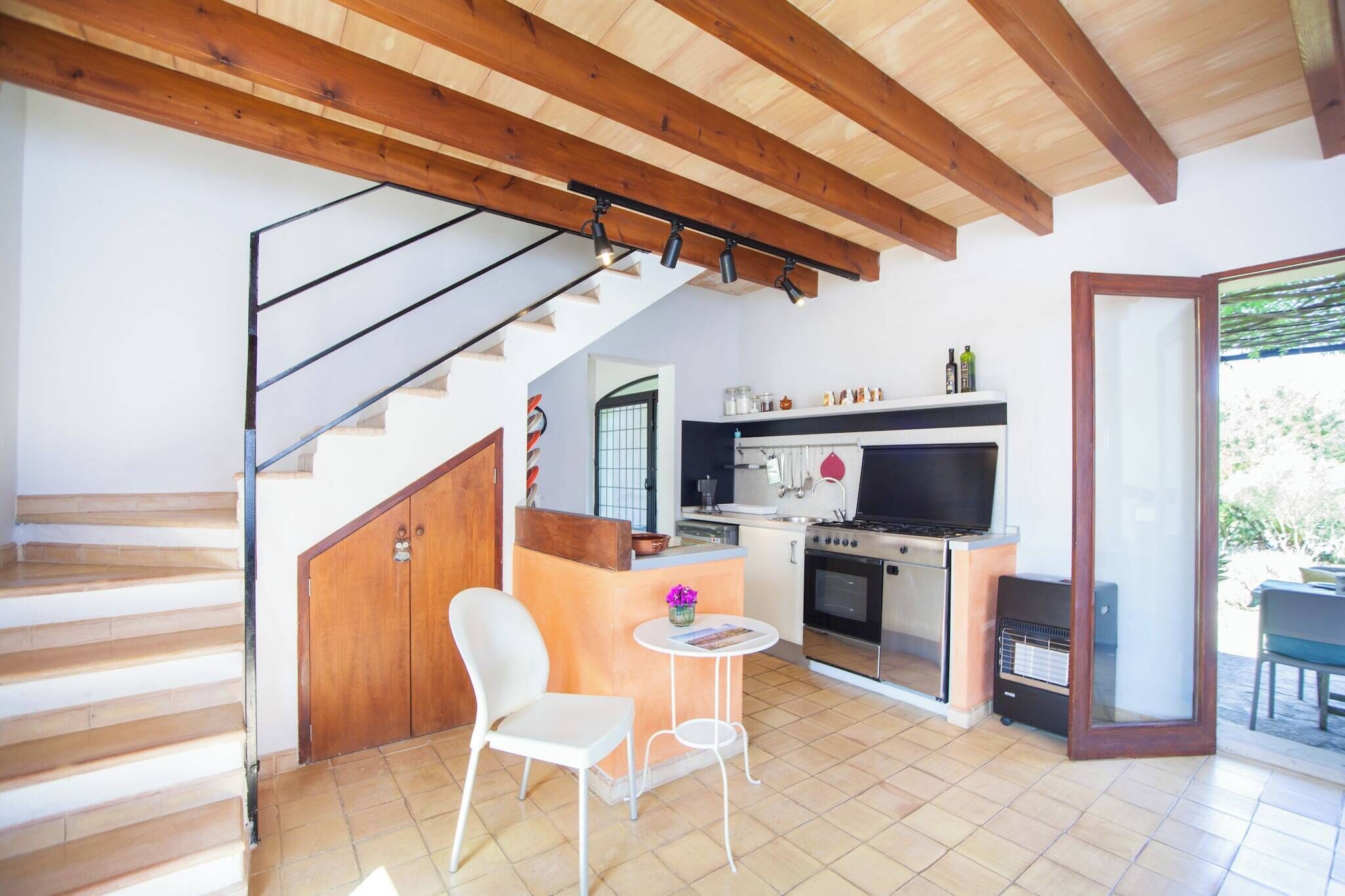 Une cuisine équipée d’une cuisinière, d’un four et d’un coin repas avec une chaise et une table.