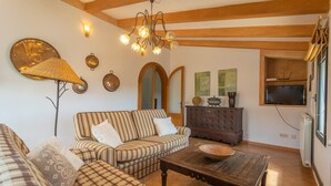 A cozy living room with striped sofas, a wooden coffee table, and a chandelier. - Es Rafal Cogolles - Villa With Private Pool (, Illes Balears)