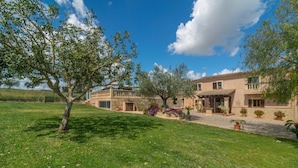 A two-story stone building with a balcony, surrounded by a well-maintained lawn and potted plants. - Es Rafal Cogolles - Villa With Private Pool (, Illes Balears)