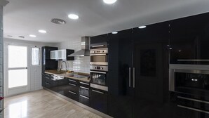 Une cuisine moderne avec des meubles de couleur noire, des appareils en acier inoxydable et une grande fenêtre.