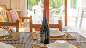 Un comedor con una mesa dispuesta para dos, una botella de vino y vistas del área de estar al aire libre.