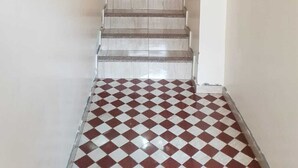Un escalier dont les marches sont recouvertes d’un motif à carreaux, menant à un palier.