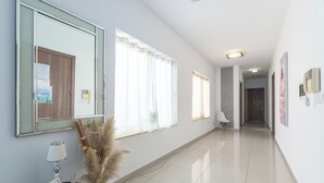 A hotel reception area with a polished floor, a reception desk with a lamp, a framed welcome sign, and a large mirror. - Amazing and Spacious Apartmet wSide Sea View (San Pawl il-Baħar)