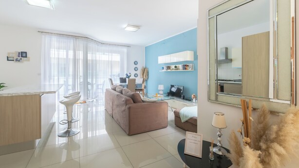 A modern living room with a sofa, a dining area, and a kitchen. - Amazing and Spacious Apartmet wSide Sea View (San Pawl il-Baħar)