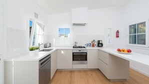 Una cocina moderna con armarios blancos, horno empotrado y un amplio ventanal que proporciona luz natural.