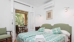 Un dormitorio con cama, una silla, una mesa y una puerta que da a un espacio exterior.