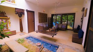 Amplia sala de estar con una hamaca colgante, una piscina pequeña y un área de descanso con sofás y una mesa de centro.