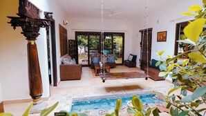 Amplia sala de estar con un ventanal grande, una hamaca y una piscina pequeña.