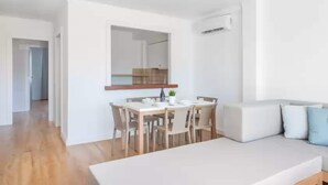 Una sala de estar moderna y minimalista con un sofá blanco, una mesa de comedor con sillas y un espejo grande en la pared.