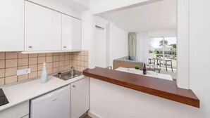 Cocina moderna con armarios blancos, encimera de madera y vistas a un comedor exterior.