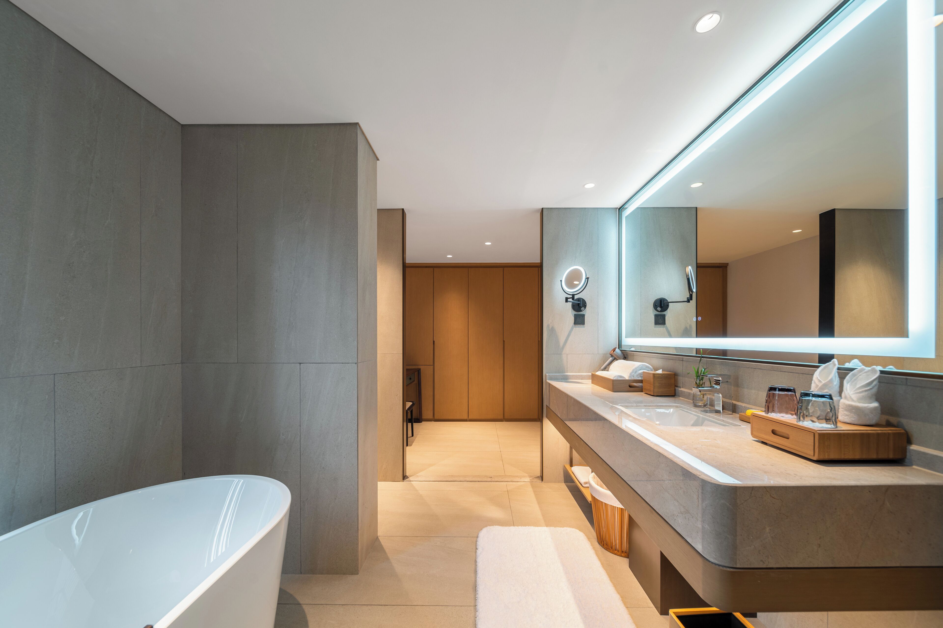 A modern bathroom with a freestanding bathtub, a large mirror, and a vanity with a sink and countertop.