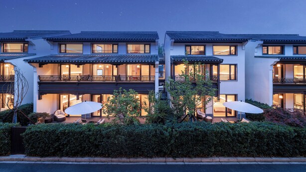 A modern hotel with multiple balconies, outdoor seating, and well-lit windows. - The Serene House (Hangzhou)