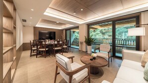 A modern dining area with a wooden table, chairs, and a large TV screen. - The Serene House (Hangzhou)