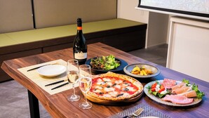 A dining table with a pizza, salad, and meat platter, a bottle of wine, and glasses. - HOTEL ALL IN TOKYO ASAKUSABASHI (Tokyo)