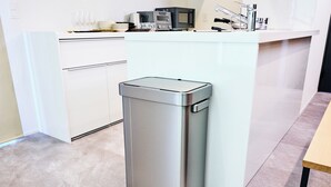 A kitchen with a stainless steel trash can, white cabinets, and a countertop with various items. - HOTEL ALL IN TOKYO ASAKUSABASHI (Tokyo)