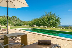 A swimming pool with a clear view of the surrounding landscape, including trees and hills.