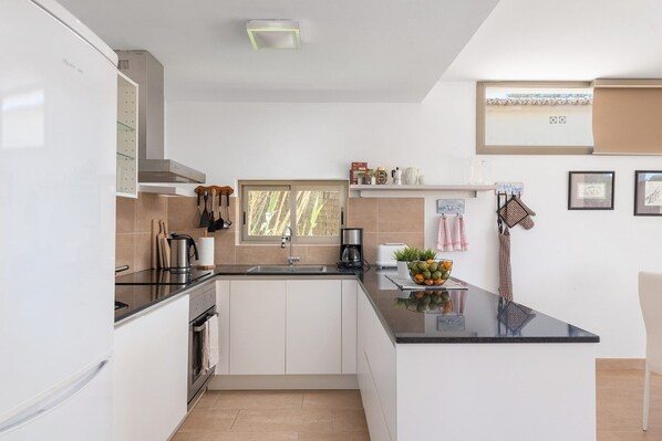 A modern kitchen with white cabinets, a black countertop, and a window.