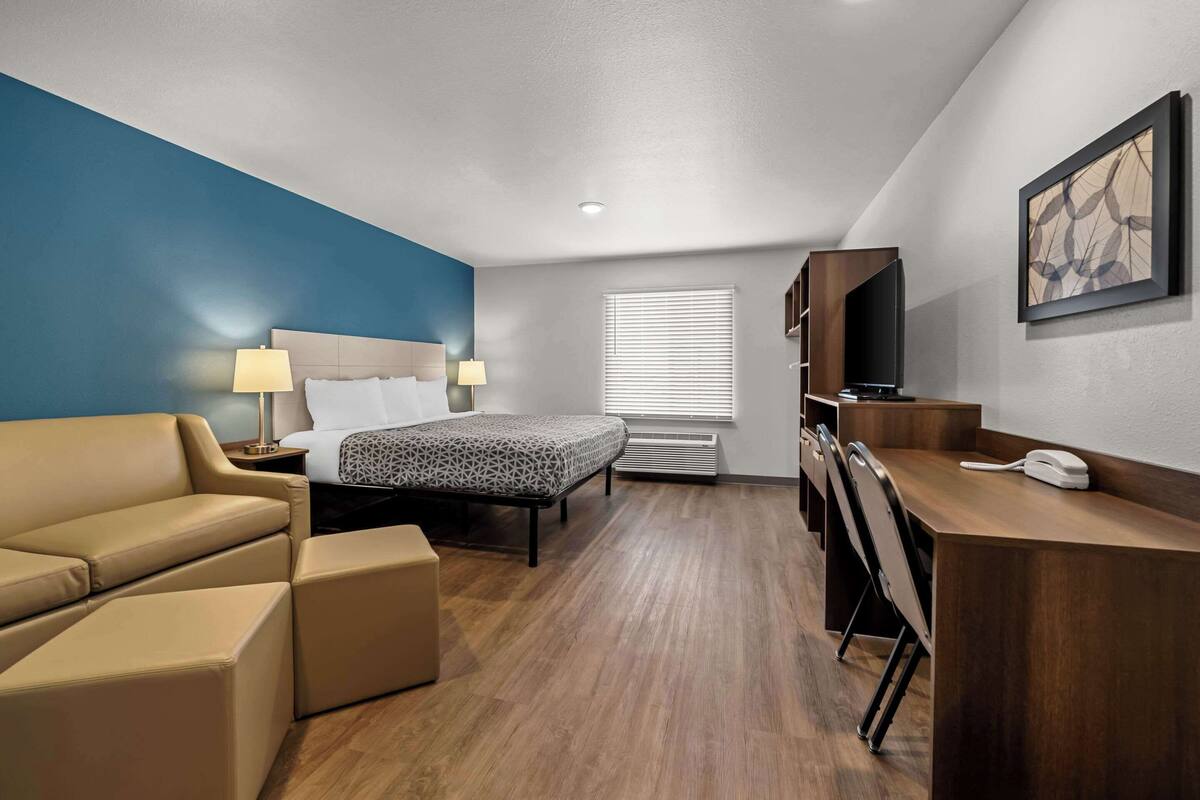 Une chambre d’hôtel équipée d’un lit, d’un bureau, d’une chaise, d’un canapé et d’une télévision.