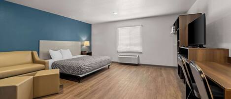 Ein modernes Hotelzimmer mit Bett, Sofa, Schreibtisch und Fernseher.