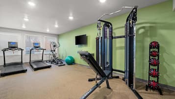 A gym with treadmills, a weight machine, and a wall-mounted TV.