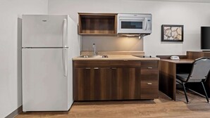 A compact kitchen with a built-in refrigerator, microwave, and sink. - Woodspring Suites Loves Park Rockford (Loves Park)