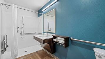 A modern bathroom with a shower, sink, and toilet.