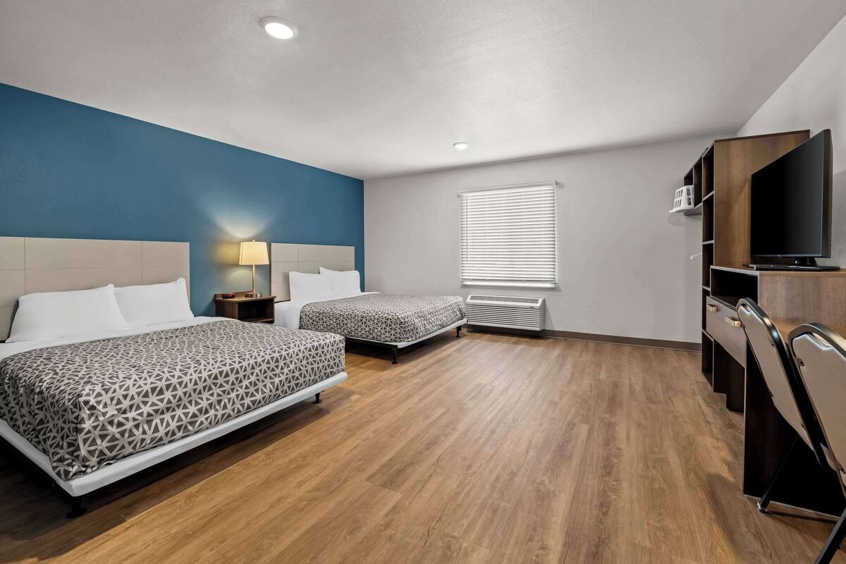 Une chambre d’hôtel avec deux lits, une télévision, un radiateur et une fenêtre avec des stores.