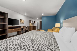 A hotel room with a bed, a desk, a chair, a TV, a microwave, and a kitchenette. - Woodspring Suites Loves Park Rockford (Loves Park)