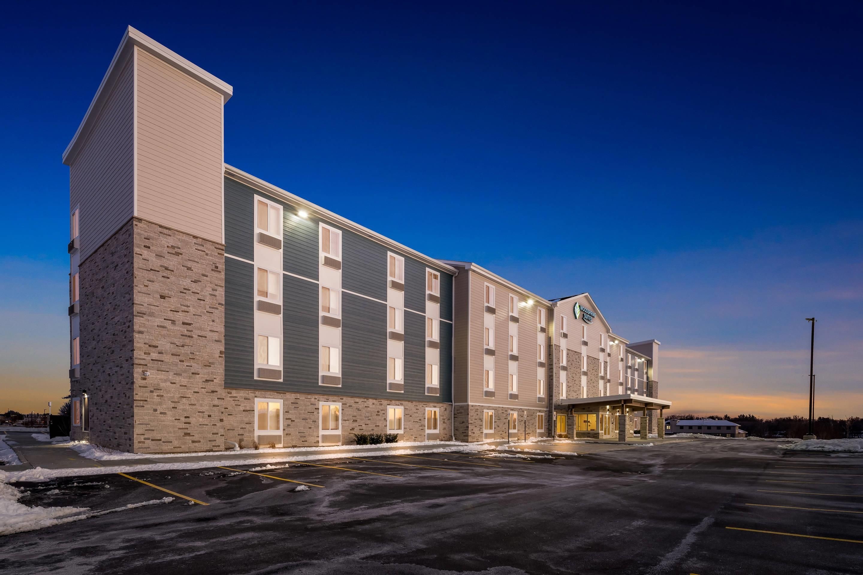 A multi-story hotel with a brick facade, large windows, and a parking lot.