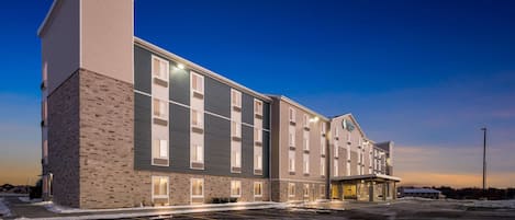 A multi-story hotel with a brick facade, large windows, and a parking lot.