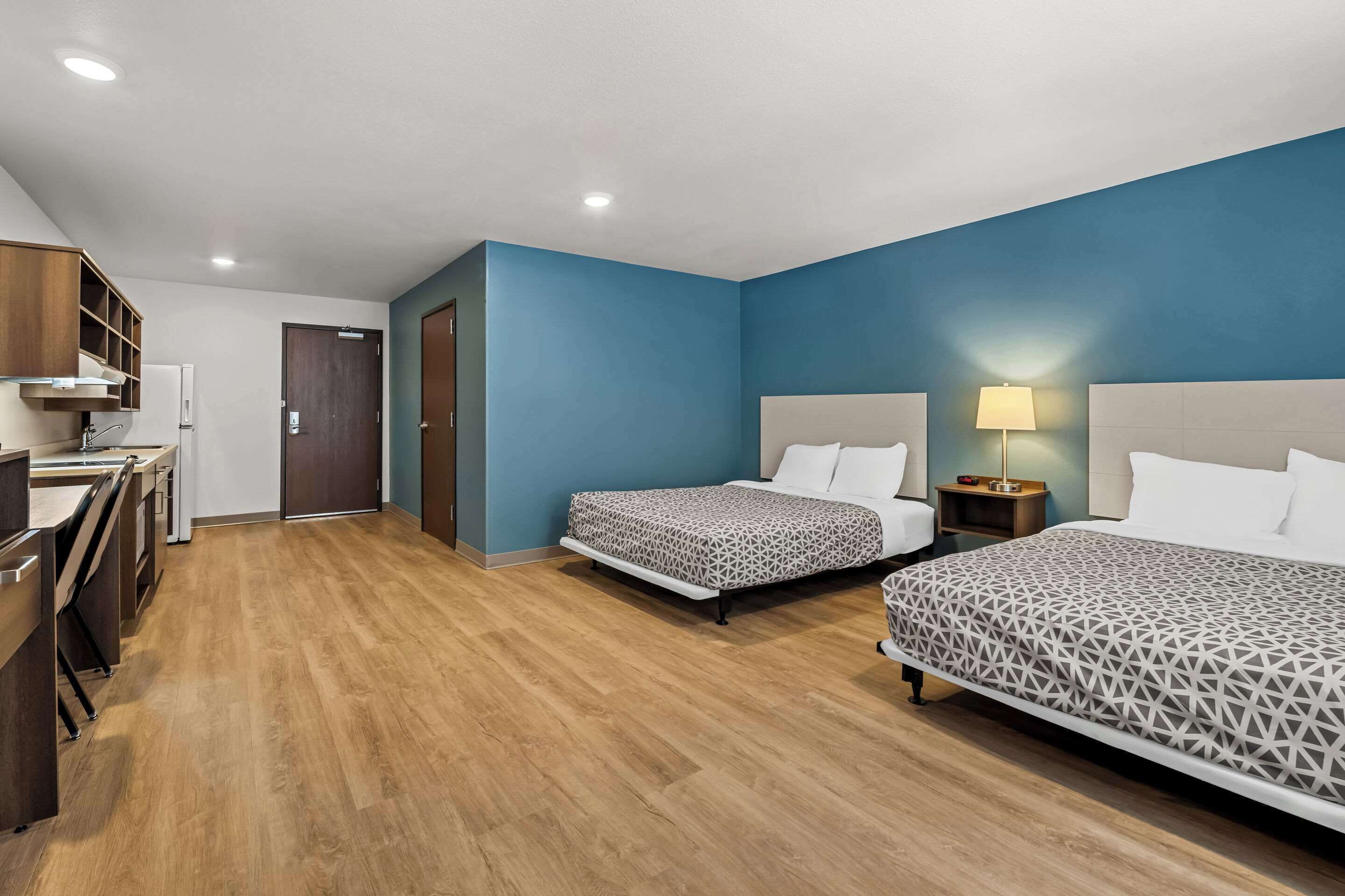 A hotel room with two beds, a desk, and a wardrobe.