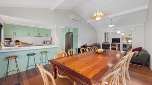 Una cocina moderna con armarios verdes, una mesa de comedor de madera y taburetes de bar.