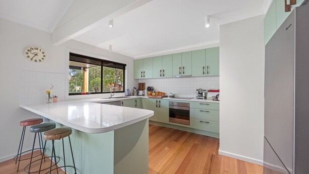Una cocina moderna con una isla grande, taburetes de bar y vistas al exterior.