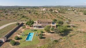 Une grande maison avec piscine, entourée d’un jardin aménagé et offrant une vue sur des collines lointaines.