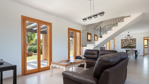 Un salon spacieux avec un grand canapé, une table basse et un escalier menant à un niveau supérieur.