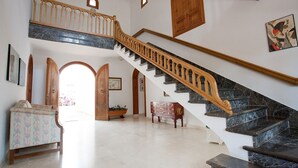 Una imponente escalera de mármol con barandillas de madera, que conduce a un piso superior.
