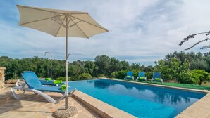 Une piscine avec des chaises longues et un parasol.