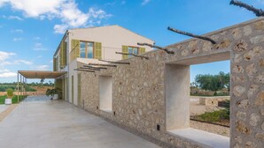 A modern house with a stone facade, a covered walkway, and a view of the countryside. - Can Mosca - Villa With Private Pool. Free Wifi (, Illes Balears)